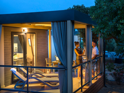 Aftenbillede af Bella Vista Chalet på Valamar Camping Krk, hvor et par nyder deres terrasse i Kroatien.