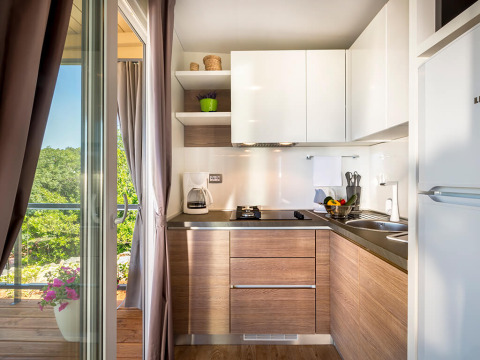 Moderne kitchenette met houten kasten en terras bij Bella Vista Home Garden Terrace, Valamar Camping Krk, Kroatië.