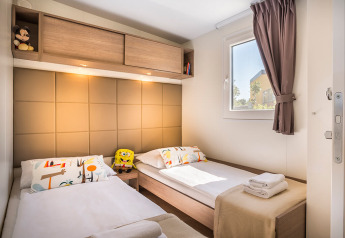 Acogedor dormitorio con dos camas individuales, juguetes y ventana en Bella Vista Home, Camping Krk, Croacia.