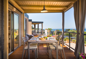 Overdekt terras met tafel, stoelen en zeezicht bij Bella Vista Home, Valamar Camping Krk, Kroatië.