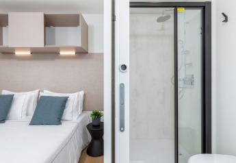 Dormitorio y baño moderno en Camping Home, Camping Arena Stupice, Croacia, con decoración acogedora.