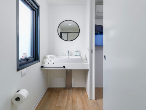 Moderne badeværelse med stort spejl, vask, håndklæder og toiletpapir på Camping Home ved Arena Stupice, Kroatien.
