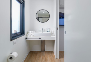 Bagno moderno con specchio rotondo, lavabo e asciugamani presso Camping Home ad Arena Stupice, Croazia.