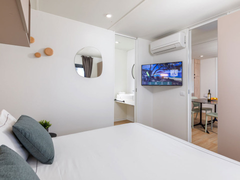 Camera da letto con letto matrimoniale, TV, aria condizionata e zona pranzo a Camping Home, Arena Stupice, Croazia.