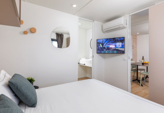 Camera da letto con letto matrimoniale, TV, aria condizionata e zona pranzo a Camping Home, Arena Stupice, Croazia.