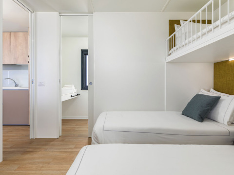 Dormitorio moderno en Camping Home «Sea View» del Camping Arena Stupice, Croacia, con camas y litera superior.