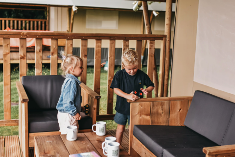 Deux enfants jouent avec des jouets sur la terrasse d'une tente safari au Camping de Kleine Wielen, Pays-Bas.
