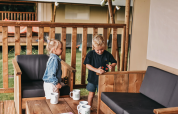 Twee kinderen spelen met speelgoed op het terras van een safaritent bij Camping de Kleine Wielen in Nederland.