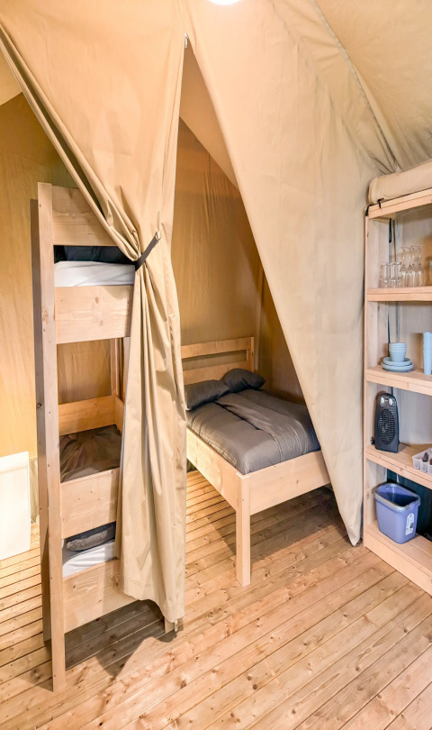 Intérieur d'une tente safari au Camping de Kleine Wielen, Pays-Bas, avec lits superposés et étagères.