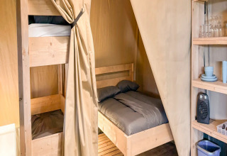 Intérieur d'une tente safari au Camping de Kleine Wielen, Pays-Bas, avec lits superposés et étagères.