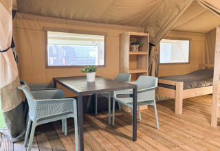 Interior of a safari tent at Campsite de Boerenzwaluw in the Netherlands with table, chairs, and bed.