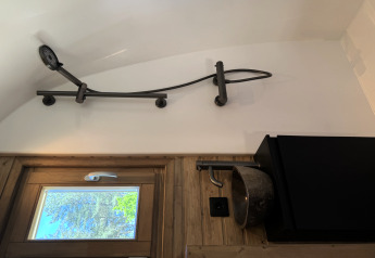 Douchekop en stenen wasbak aan de muur in Cabin at Thuysgrond, Nederland, binnenaanzicht met raam.