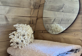 Dos toallas suaves, un espejo y flores secas sobre madera en la Cabin at Thuysgrond, Países Bajos.