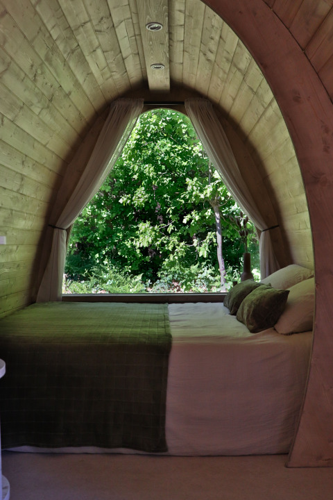 Schlafzimmer in einer Holzhütte mit großem Fenster und Naturblick, Cabin at Thuysgrond, Niederlande.
