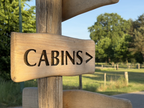 Holzschild mit eingraviertem 'CABINS'-Text zeigt den Weg zu den Hütten bei Thuysgrond, Niederlande.