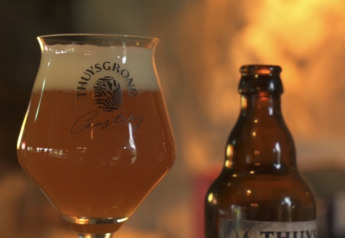 Ein Glas und eine Flasche Thuy's Tripel Bier auf einem Tisch im gemütlichen Ambiente einer Glamping-Unterkunft.
