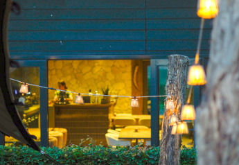Buitenaanzicht van glamping accommodatie met sfeervolle lichtslinger en warm verlicht interieur zichtbaar.