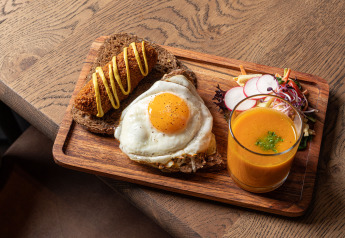 Frühstücksteller beim Glamping mit Spiegelei auf Brot, Croquette, Salat und einem Glas Saft.
