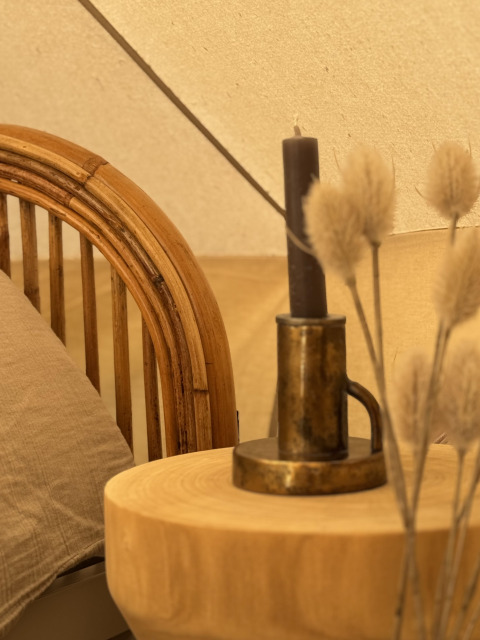 Coin chaleureux d'une tente Bell avec table en bois, bougeoir en laiton, bougie, coussin et plantes.