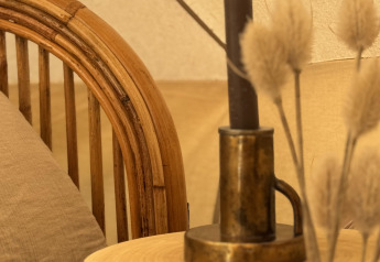 Gemütliche Ecke im Bell Zelt mit Holztisch, Messingleuchter, schwarzer Kerze und Kissenbezug.