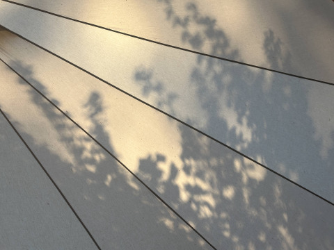 Ombre di foglie su tessuto beige di tenda Bell con linee scure, foto scattata in un tipì.