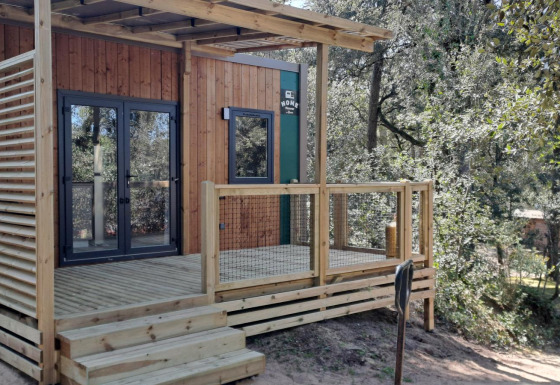 Homeflower Premium 18m² lodge featuring a modern wooden deck and surrounded by trees in a scenic area.