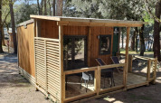 Homeflower Premium 18m² lodge met houten terras, gelegen in het bos op Flower Camping La Sagne in Frankrijk.
