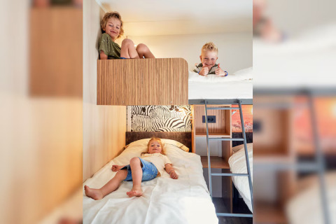 Three happy kids play on bunk beds in a SunLodge Mobile Home Katsura at Campsite Pra’delle Torri, Italy.