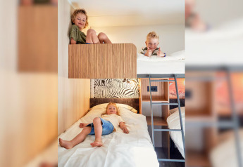Tres niños sonrientes juegan en literas dentro de SunLodge Mobile Home Katsura en el Camping Pra’delle Torri en Italia.