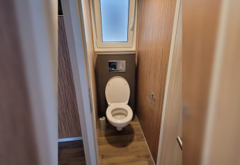 Baño con inodoro y ventana en SunLodge Mobile Home Katsura del Camping Pra'delle Torri, Italia.