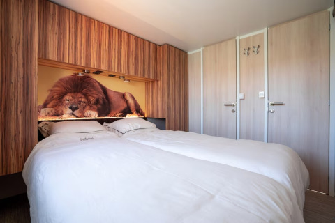 Chambre moderne avec lit double et grande fresque d’un lion endormi au SunLodge Mobile Home en Italie.