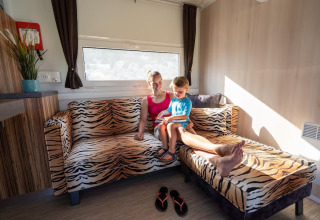 Mère et enfant assis sur un canapé tigre dans un SunLodge Mobile Home à Marina di Venezia, Italie.