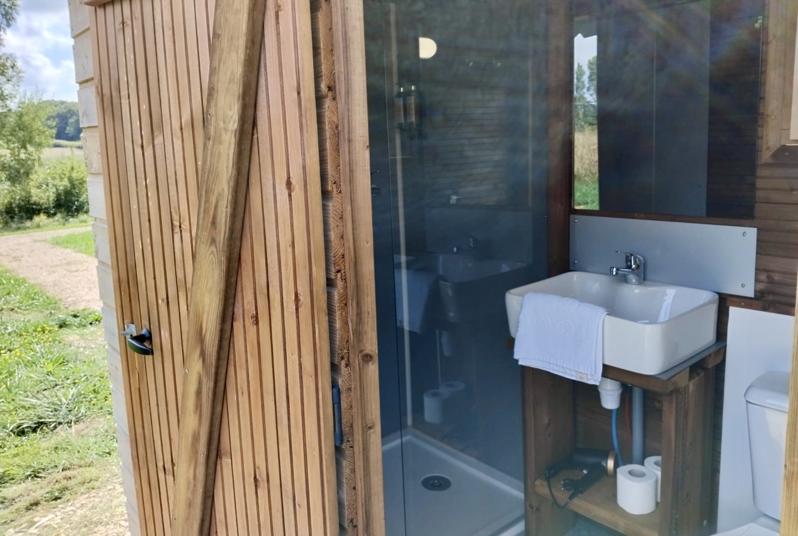 Kleine badkamer met wastafel en douche in houten tiny house bij Cabane «Perdue», Domaine des Feuilles, Frankrijk.