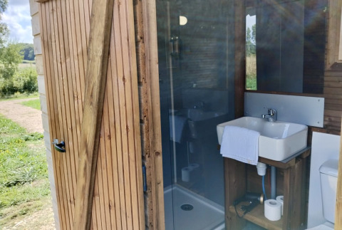 Kleine badkamer met lavabo en douche in een houten tiny house bij Cabane «Perdue», Domaine des Feuilles, Frankrijk.