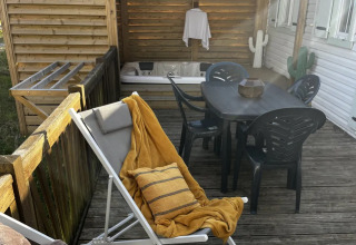 Terrasse de Mobil-home Premium au camping Les Franquettes en France avec transat, table et jacuzzi.