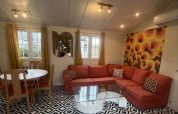Salon chaleureux du Premium Mobile Home au Camping Les Franquettes avec canapé orange et décor rétro.