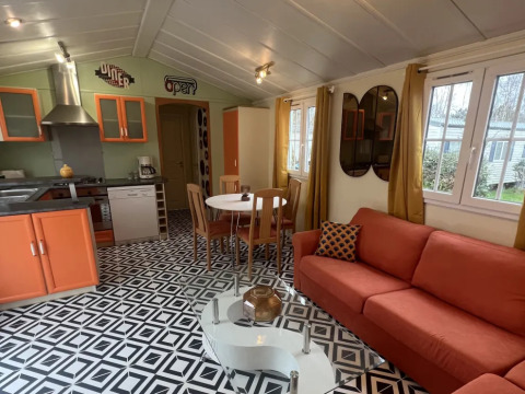 Interiør af Premium Mobile Home Spa med moderne køkken, orange sofa, geometrisk gulv og runde spejle.
