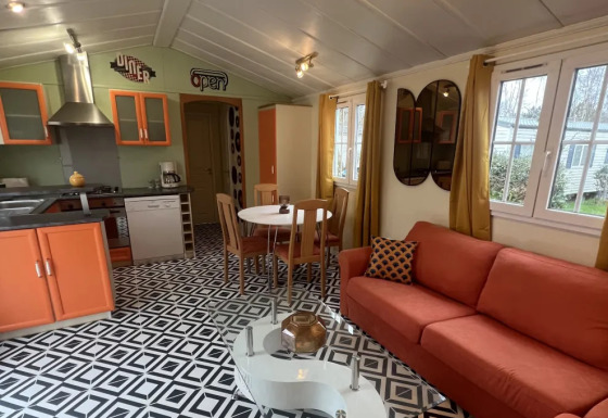 Interiør af Premium Mobile Home Spa med moderne køkken, orange sofa, geometrisk gulv og runde spejle.