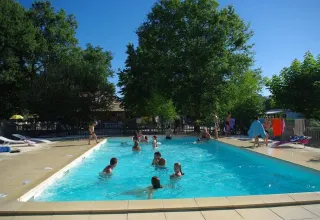 Udendørs swimmingpool ved Premium Mobile Home, Camping Les Franquettes, Frankrig med gæster i vandet.