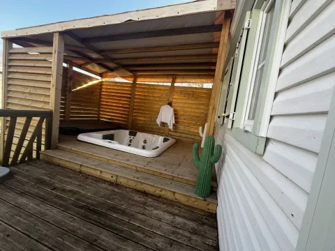 Udendørs terrasse med overdækket jacuzzi, håndklæde, kaktusdekoration og trægulv ved mobilhome.