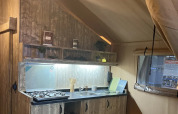 Interior view of the safari tent Lodge «Woody 38» featuring a rustic kitchen at Campsite Les Franquettes.