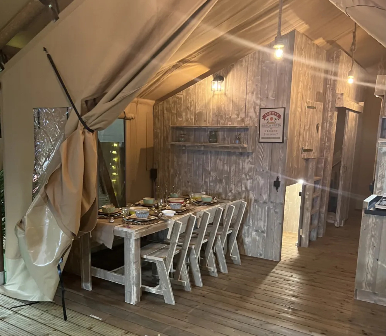 Binnenaanzicht van safari-tent Lodge Woody 38 op Camping Les Franquettes in Frankrijk, met gedekte eettafel.