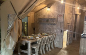 Vista interna del Lodge Woody 38, tenda safari al Campeggio Les Franquettes in Francia, con tavolo apparecchiato.