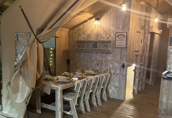 Innenansicht des Safari-Zeltes Lodge Woody 38 auf dem Campingplatz Les Franquettes in Frankreich mit gedecktem Tisch.