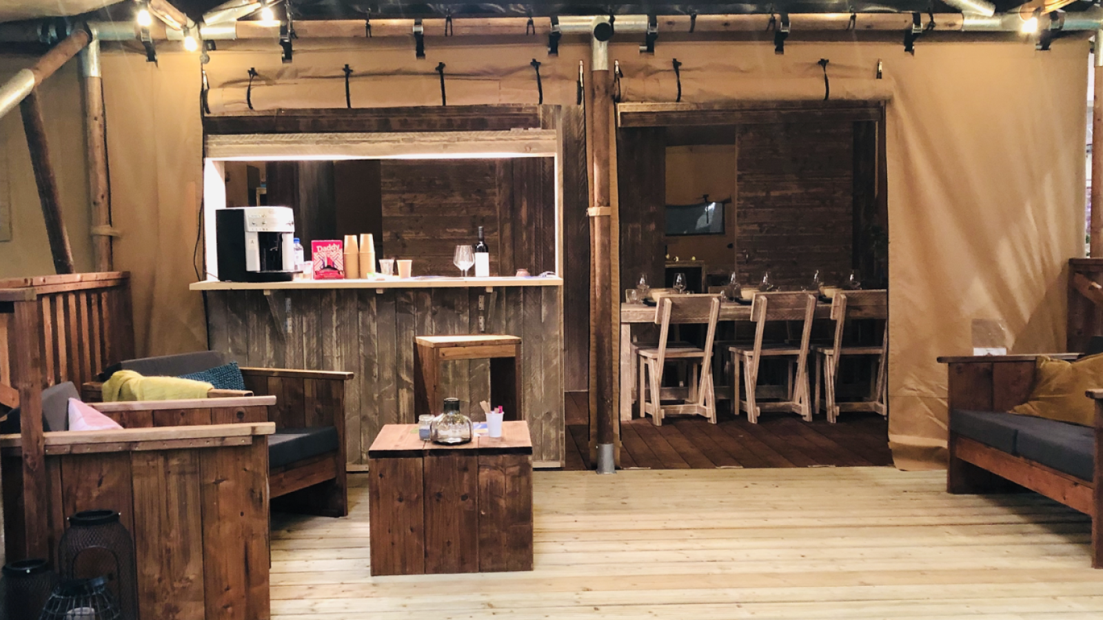 Luxe safaritent met houten lounge en eethoek bij Camping Les Franquettes in Frankrijk.