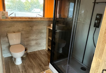 Baño con inodoro y ducha en una tienda safari de lujo en el camping Les Franquettes en Francia.