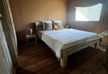 Dormitorio en tienda safari de lujo en Les Franquettes, Francia, con cama doble y decoración de madera.