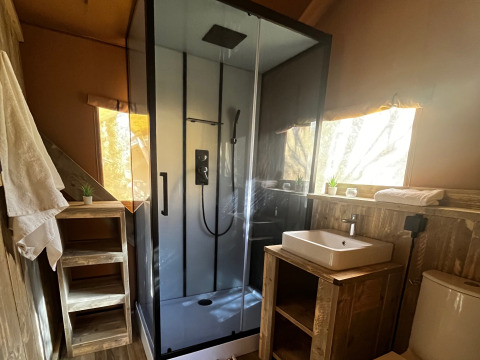 Bagno all’interno di una tenda safari di lusso con doccia, lavabo e WC al campeggio Les Franquettes in Francia.