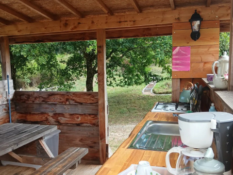 Rustic outdoor kitchen with wooden counters, coffee maker, and nature views at Bell tent “6M,” Campsite Junora.