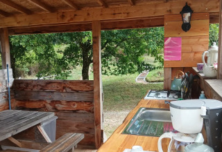 Rustic outdoor kitchen with wooden counters, coffee maker, and nature views at Bell tent “6M,” Campsite Junora.